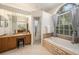 Well-lit bathroom with a soaking tub, arched window, and vanity at 4324 Auston Way, Palm Harbor, FL 34685