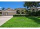 Charming home features a lush green lawn, mature landscaping, and an attached two-car garage at 4324 Auston Way, Palm Harbor, FL 34685