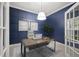 Modern home office featuring navy blue walls, wood paneling, light wooden desk, and minimalist decor at 4324 Auston Way, Palm Harbor, FL 34685