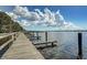Scenic waterfront view featuring a wooden dock with boat slips and tranquil water under a cloudy sky at 4324 Auston Way, Palm Harbor, FL 34685