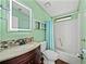 Colorful bathroom with green walls, modern vanity, and tub shower at 4920 Blanco Dr, Zephyrhills, FL 33541