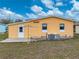 Back exterior of home with white door and surrounding green lawn at 4920 Blanco Dr, Zephyrhills, FL 33541