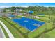 Aerial view of a new blue basketball court, park and clubhouse in a modern home community and lush landscaping at 5732 Bluestar Ct, Lakewood Ranch, FL 34211