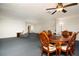 Open living space with blue carpet, ceiling fan, and round wooden dining table with upholstered chairs at 6025 Shore S Blvd # 410, Gulfport, FL 33707