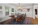 Spacious dining room with a large wooden table, seating for six, and a colorful rug, under a modern woven light fixture at 6835 S Shamrock St, Tampa, FL 33616