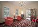 Bright living room featuring large windows, vintage furniture, and vibrant floral carpet at 6835 S Shamrock St, Tampa, FL 33616