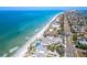 Stunning aerial view of beachfront homes, pristine white sands, and turquoise waters along the coastline at 920 Spruce Dr, Belleair Beach, FL 33786