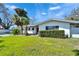Charming single story home featuring a well-manicured lawn, red door, and tropical palm trees at 920 Spruce Dr, Belleair Beach, FL 33786