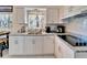 Bright kitchen featuring white cabinets, stainless steel sink, granite countertops, and modern appliances at 920 Spruce Dr, Belleair Beach, FL 33786
