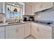 Updated kitchen featuring white cabinets, stainless steel sink, granite countertops, and tile backsplash at 920 Spruce Dr, Belleair Beach, FL 33786