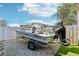 Mako boat parked and secured on trailer on a gravel plot, with a fenced yard and neighborhood in the background at 1015 Coldstream Ct, Tarpon Springs, FL 34689