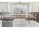 Close-up of kitchen area with white cabinets, farmhouse sink, and herringbone backsplash beneath a window at 1015 Coldstream Ct, Tarpon Springs, FL 34689