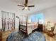 Cozy bedroom featuring a four-poster bed, hardwood floors, ceiling fan, rocking chair, and window with natural light at 1309 Hillside Dr, Tarpon Springs, FL 34689
