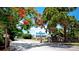 Charming blue two-story home with a white porch, framed by vibrant red flowering trees at the entrance to Robinson Preserve at 1320 Bottlebrush Dr, Bradenton, FL 34208