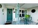 Inviting front porch with seating area, a glass-topped table, teal door, and decorative wrought iron accents at 1320 Bottlebrush Dr, Bradenton, FL 34208