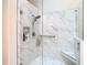 Elegant shower with marble-patterned tile, built-in shelf, and glass door at 13439 Norman Cir, Hudson, FL 34669
