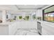 Kitchen boasts white cabinets, marble countertops, stainless steel appliances, and a farmhouse sink with a view at 14333 Lake Magdalene Blvd, Tampa, FL 33618