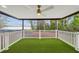 Scenic covered patio featuring artificial grass, a ceiling fan, and views of the lake at 14333 Lake Magdalene Blvd, Tampa, FL 33618