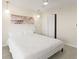 This bedroom has a large white bed, wood-look floors, modern light fixtures, and a neutral color palette at 19111 Vista Bay Dr # 401, Indian Shores, FL 33785