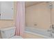 Cozy bathroom features a tub/shower combo with pink curtain, and a white tiled floor at 2207 Boxwood Way, Brandon, FL 33511
