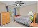 This bedroom features a ceiling fan, a wooden dresser, a window letting in light and simple decor for a restful retreat at 2207 Boxwood Way, Brandon, FL 33511
