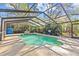 Backyard pool with enclosure features blue tile trim and an outdoor seating area with a green umbrella at 2207 Boxwood Way, Brandon, FL 33511