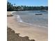Picturesque view of a sandy beach meeting calm water with boats in the distance at 2700 Bayshore Blvd # 2308, Dunedin, FL 34698