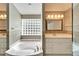 Bathroom with a glass block window, a soaking tub, vanity sinks, and decorative lighting at 3904 Executive Cir, Plant City, FL 33566