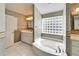 Bright bathroom with a soaking tub, a glass block window and a white vanity at 3904 Executive Cir, Plant City, FL 33566