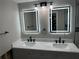 Bathroom vanity featuring double sinks, marble countertop, modern fixtures, and lighted mirrors at 3934 Huntington Ne St, St Petersburg, FL 33703