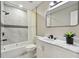 Well-lit bathroom with marble top vanity, black hardware, decorative plant, and bathtub shower combo at 3934 Huntington Ne St, St Petersburg, FL 33703