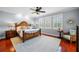A serene main bedroom with hardwood floors, ceiling fan, plantation shutters and sunburst mirror at 4603 S Bartlett St, Tampa, FL 33611