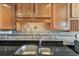 Close up on the kitchen sink featuring black granite countertops, updated hardware, and stylish tile backsplash at 5940 Pelican Bay S Plz # 1205, Gulfport, FL 33707