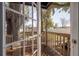 View from inside through a glass door to the backyard, featuring trees, a wooden deck, and white fencing at 6907 N 12Th St, Tampa, FL 33604