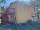 Rear view of a yellow two-story home with red deck and basketball hoop at 7111 N 53Rd St, Tampa, FL 33617