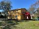Exterior view of a yellow two-story home with a red deck and a spacious backyard at 7111 N 53Rd St, Tampa, FL 33617