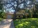 Charming yellow home with a well-maintained lawn and mature trees creating a shaded front yard at 7111 N 53Rd St, Tampa, FL 33617