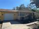 Inviting yellow home with front porch, attached garage, and manicured landscaping for enhanced curb appeal at 7111 N 53Rd St, Tampa, FL 33617
