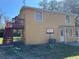 Back of a two-story yellow home with a red deck, stairs, and a basketball hoop at 7111 N 53Rd St, Tampa, FL 33617