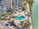 Aerial view of the community pool and lounge area surrounded by palm trees near the water at 7400 Sun Island Drive S # 712, South Pasadena, FL 33707