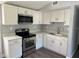 A kitchen featuring stainless steel appliances, gray vinyl flooring, and white cabinets at 7909 N Packwood Ave, Tampa, FL 33604