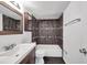 Bathroom featuring dark brown tiling, bathtub and shower, toilet, and white sink at 108 Pompano Se Dr # A, St Petersburg, FL 33705