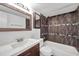 Bathroom featuring dark brown tiling, bathtub and shower, toilet, and white sink at 108 Pompano Se Dr # A, St Petersburg, FL 33705