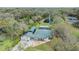 An aerial view of home with a green metal roof, screened pool and a private pond surrounded by lush greenery at 12508 Balm Riverview Rd, Riverview, FL 33579