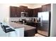 Well-equipped kitchen with stainless steel appliances, dark wood cabinetry, and bar seating at 14352 Editors Note St, Ruskin, FL 33573