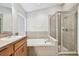 Bright bathroom featuring a soaking tub with tile surround and a glass-enclosed shower at 15807 Leatherleaf Ln, Land O Lakes, FL 34638
