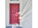 Close up of a stylish red front door, set against a bright white exterior wall at 15807 Leatherleaf Ln, Land O Lakes, FL 34638