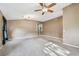 Bright living room with a ceiling fan, neutral walls, plush carpeting, and tile flooring in the entryway at 15807 Leatherleaf Ln, Land O Lakes, FL 34638