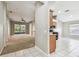 Open-concept living room seamlessly connects to the kitchen and the screened-in porch with plush carpet and white tile at 15807 Leatherleaf Ln, Land O Lakes, FL 34638