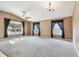 Spacious living room featuring plush carpeting, high ceilings, large windows, and ceiling fans at 15807 Leatherleaf Ln, Land O Lakes, FL 34638